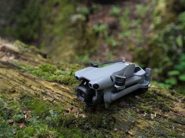 Folded DJI Mini 5 Pro resting on a moss-covered log
