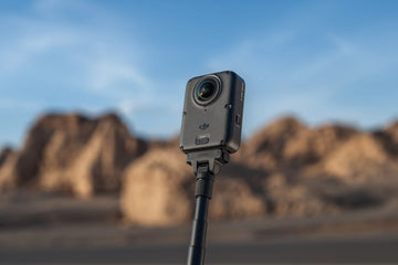 DJI Osmo 360 II mounted on a pole in front of sunlit rock formations